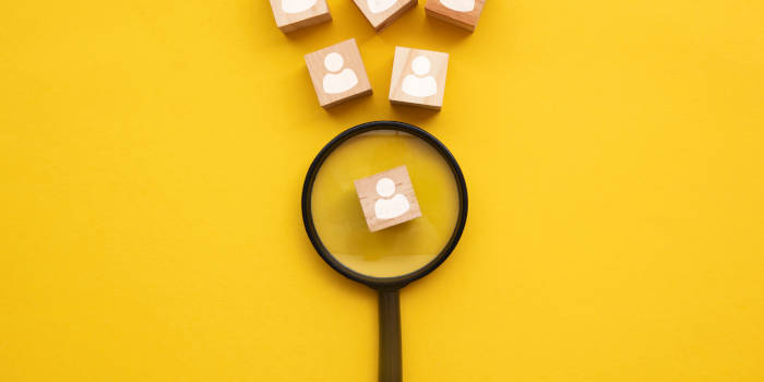 A magnifying glass examining a cube with a person profile on it.