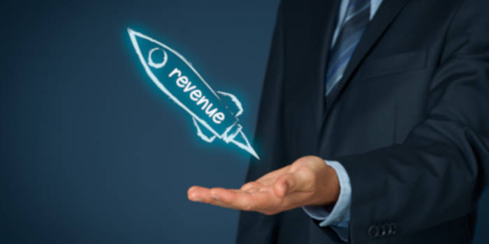 A businessman pushing a rocket with a sign revenue on it
