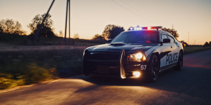 Police car in pursuit on a dirt road.